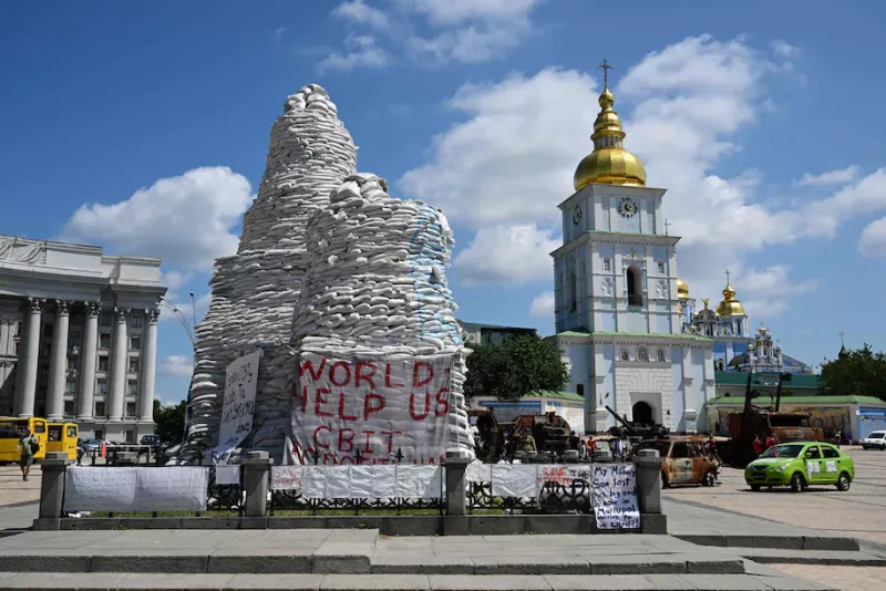A banner reading "World help us" is displayed on the covered and protected monument of Olga of Kiev, in central Kyiv, Ukraine, on June 30. 