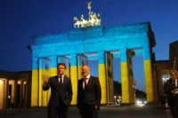 French President Emmanuel Macron and German Chancellor Olaf Scholz stand in front of the Brandenburg Gate, illuminated in the colors of the Ukrainian flag, in Berlin on May 9. Sean Gallup/Getty Images
