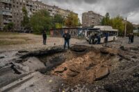 Investigators examine a crater and a damaged bus after a missile strike in Dnipro, Ukraine, on Monday amid Russia's invasion. (Dimitar Dilkoff/AFP/Getty Images)