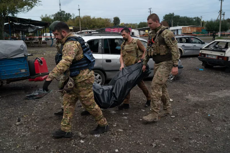 Ukrainian servicemen carry a bag containing the body of a person after a Russian attack in Zaporizhzhia, Ukraine, on Friday. (Leo Correa/AP) 