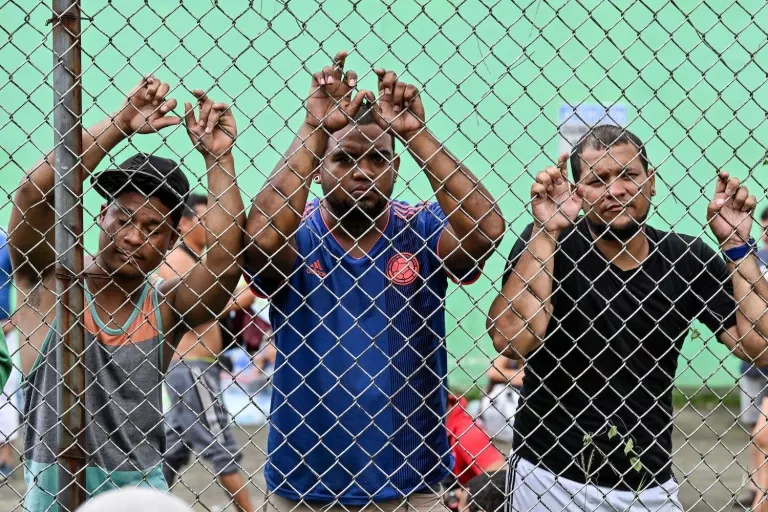 Venezuelan migrants stand by a fence at an improvised shelter in Panama City, on Oct.23. LUIS ACOSTA/AFP via Getty Images