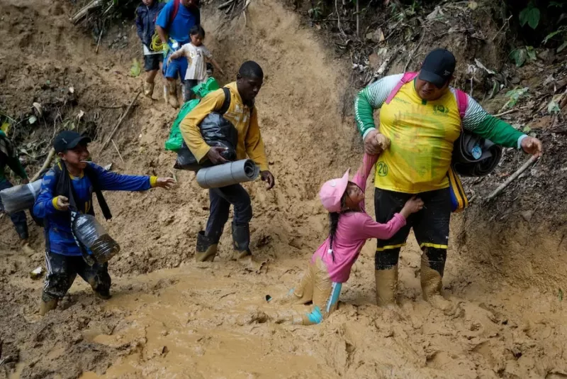 Personas migrantes, incluyendo niños, cruzan el Tapón de la selva del Darién desde Colombia hacia Panamá, con la esperanza de llegar a Estados Unidos, el 15 de octubre de 2022. (Fernando Vergara/AP) 