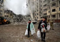 Residents of Dnipro, Ukraine, on Jan. 15 carry their belongings from a building destroyed by a Russian missile strike. (Sergei Chuzavkov/AFP/Getty Images)