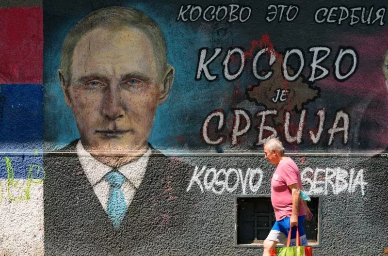 A man passes by graffiti depicting Russian President Vladimir Putin, reading: “Kosovo is Serbia” in Belgrade, Serbia, on Aug. 1. (Darko Vojinovic/AP) 
