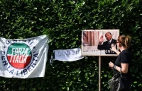 Una mujer toca una imagen de Silvio Berlusconi en un improvisado tributo fuera de su residencia en Arcore, el lunes.GABRIEL BOUYS (AFP)
