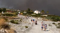 Tourists are evacuated as wildfire burns near Lindos, on the island of Rhodes, Greece, on July 22. A new report finds that heat waves in the US and Europe this year would have been "virtually impossible" without climate change. Lefteris Damianidis/Reuters