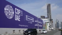 Des voitures passent devant l'entrée de la COP28. Dubai, 27 novembre 2023. — © Kamran Jebreili / keystone-sda.ch