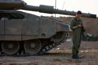 An Israeli soldier using a mobile phone near the Gazan-Israeli border, November 2023. Alexander Ermochenko / Reuters.